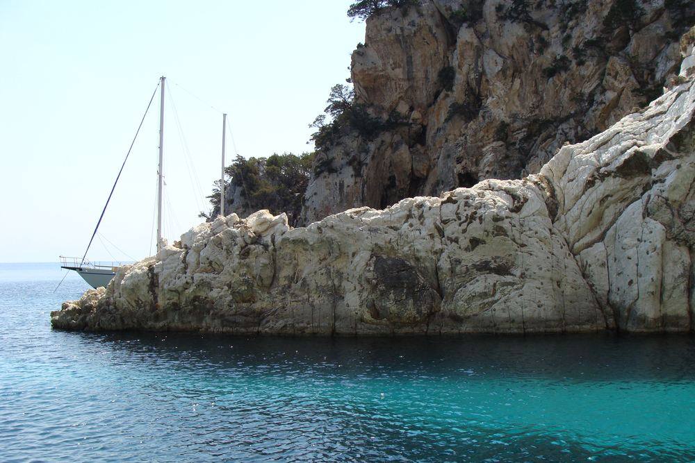 A single Sailing Yacht anchored under the pale limestone headland of Atokos in the Ionian